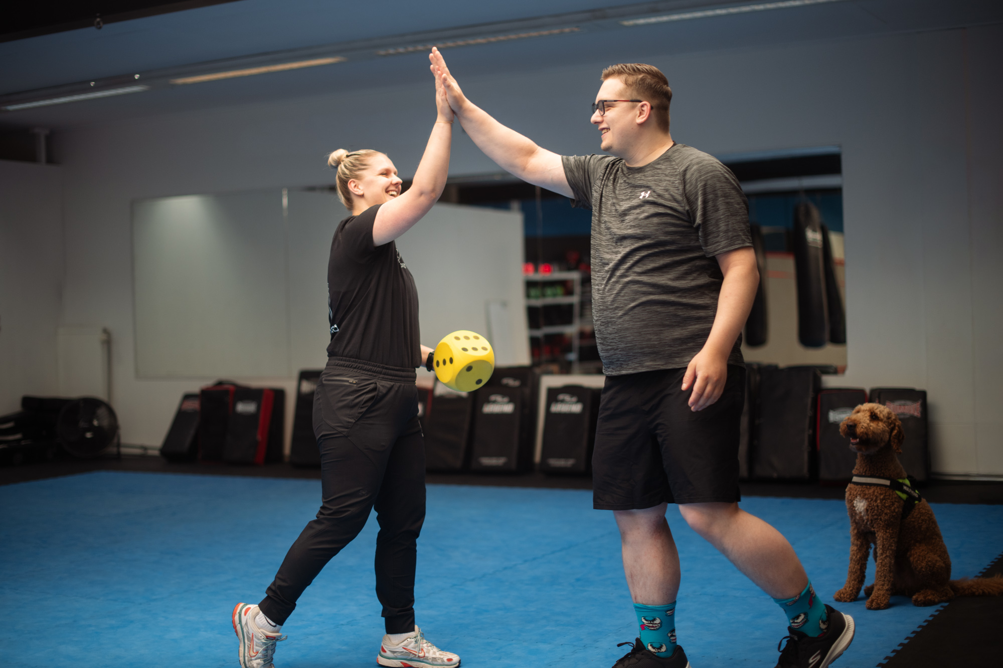 Twee mensen geven elkaar een high five tijdens een beweegoefening bij Trainmetzorg.